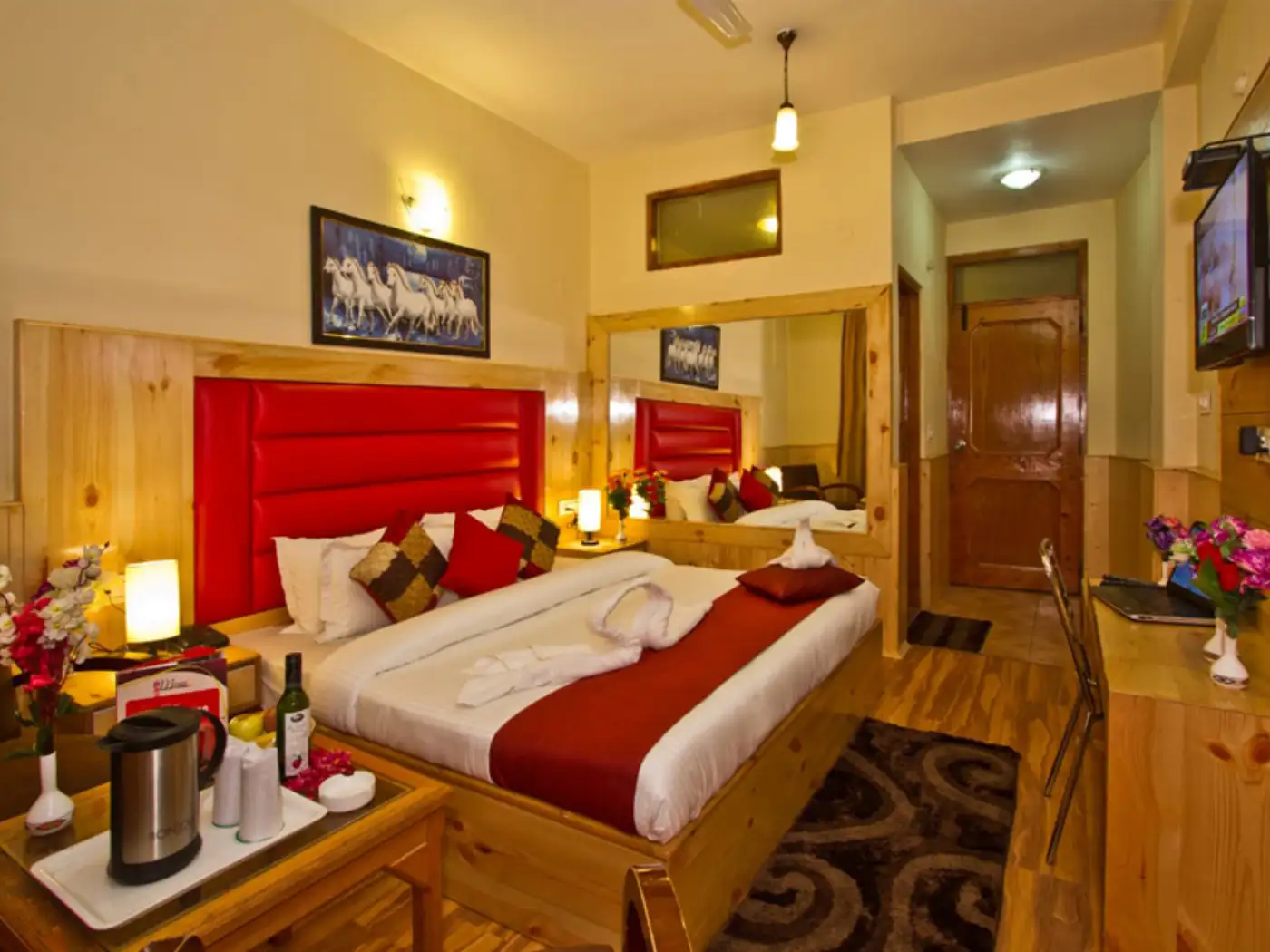 Romantic hotel room with rose petals on bed, wine