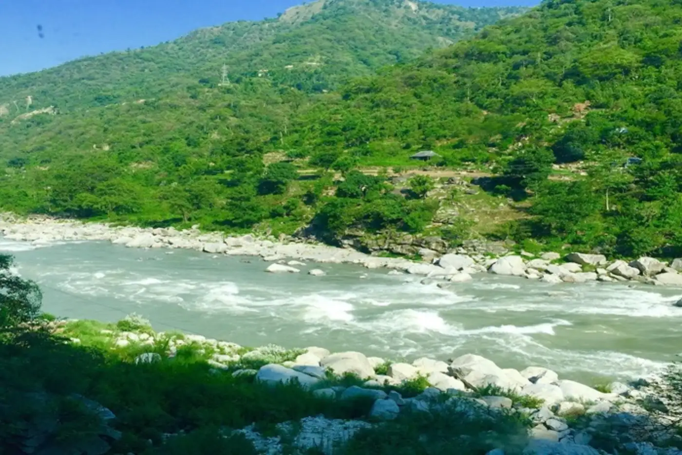 Scenic river flowing through a lush green valley, mountains in background