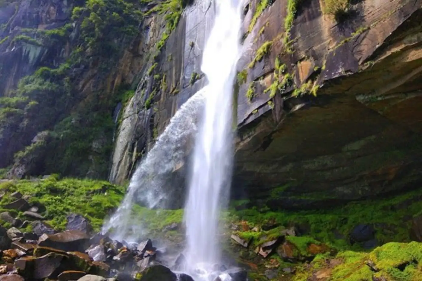 Majestic waterfall cascading down a rocky cliff surrounded by lush greenery.