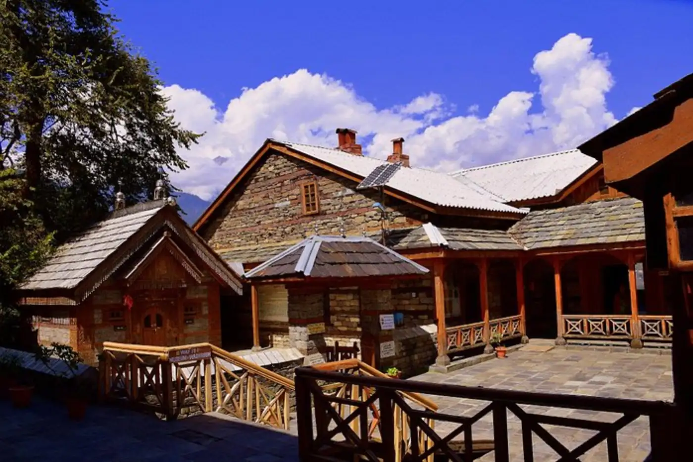 Beautiful wooden temple in Manali, India with checkered floor and mountain backdrop.